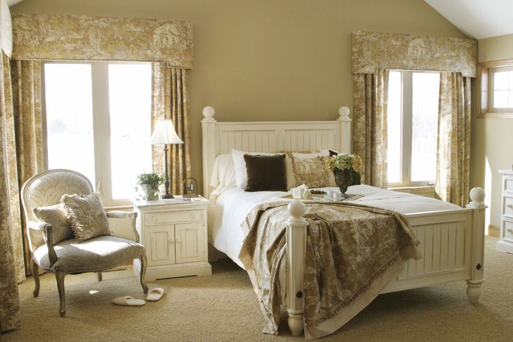 Нежная спальная комната для гостей в стиле кантри с элементами прованса: кованая кровать, цветочный текстиль, светлая мебель.